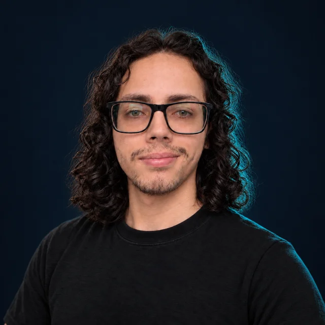 Retrato de Juan David Gaitán, arquitecto de software, con gafas y cabello rizado