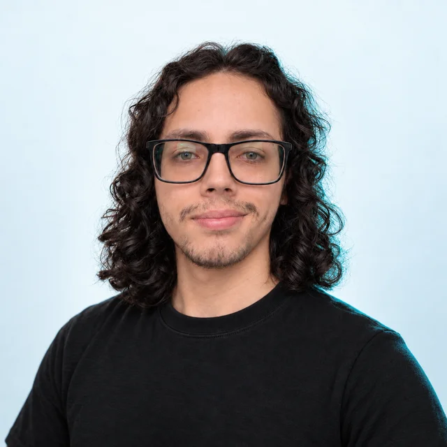 Retrato de Juan David Gaitán, arquitecto de software, con gafas y cabello rizado